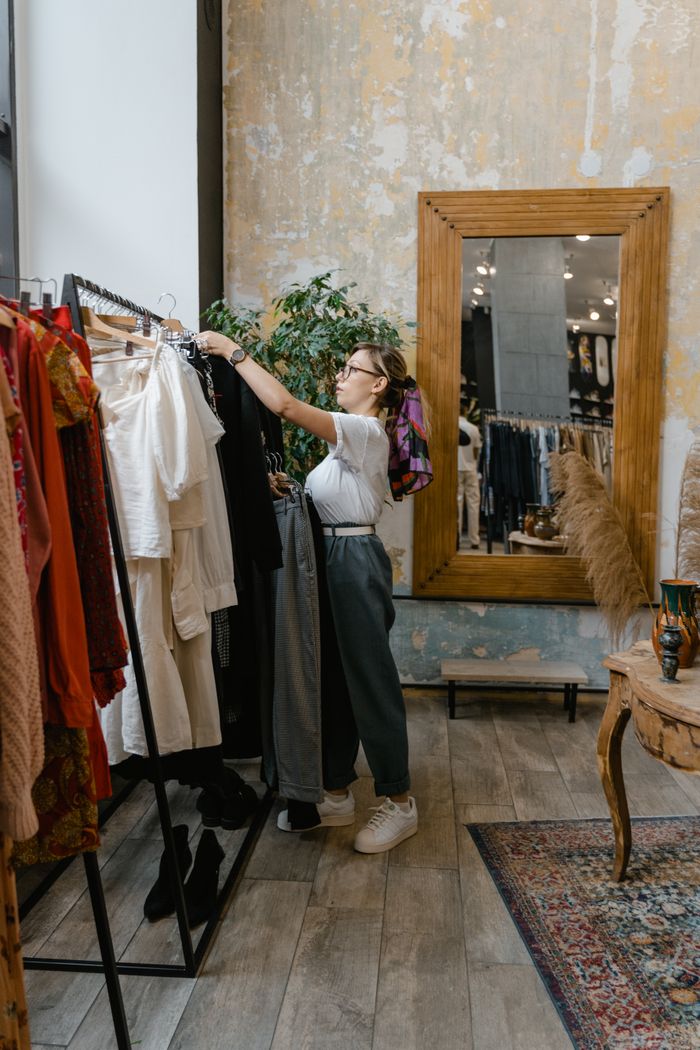 Woman browsing clothes rack in contemporary clothing store interior.